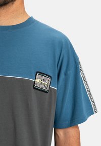 Korte mouwen t-shirt in blauw en grijs katoen, met een logopatch op de borst en een patroonaccent op de mouw.