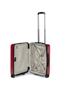 Valigia rigida rossa con manico retrattile, scomparti con zip, rivestimento interno beige e cinghie incrociate per fissare il contenuto.