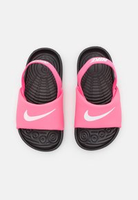 Różowe klapki Nike z czarną teksturowaną podeszwą, z szeroką wsuwką i wyraźnym białym logo z przodu. Projekt wsuwany, otwarty tył.