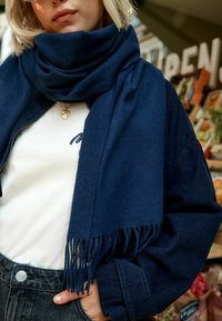 Tumed sinine sall, pehmest kangast, fraktsiooniga äärtega. Kantud valge särk üle, tumeda tekstuuriga ribaliselt jope all.