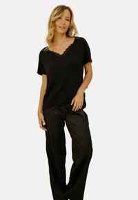 Top noir à manches courtes avec décollet�é en V et bord en dentelle. Assorti à un pantalon noir large et plissé. Tissu doux et coupe décontractée.