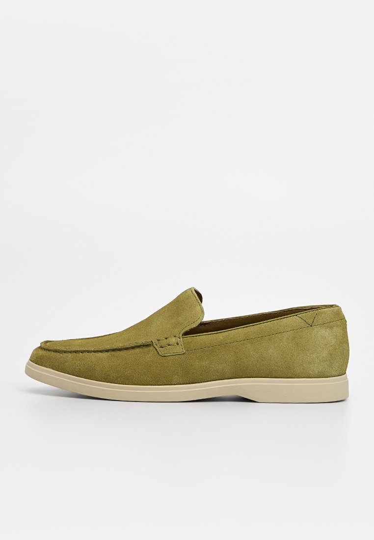 Chaussures à enfiler en daim vert olive avec une semelle en caoutchouc basse, des détails cousus à l'avant et un design à bout arrondi.
