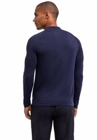 Marineblaues, langärmliges Sportshirt mit strukturiertem Schulterdesign und enganliegenden Ärmeln, hergestellt aus dehnbarem Stoff für Flexibilität.