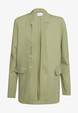 Jasnozielona kurtka z kołnierzem stójkowym, z przodu na zamek błyskawiczny i trzema guzikami. Posiada dwie boczne kieszenie o gładkim, teksturowanym wykończeniu.