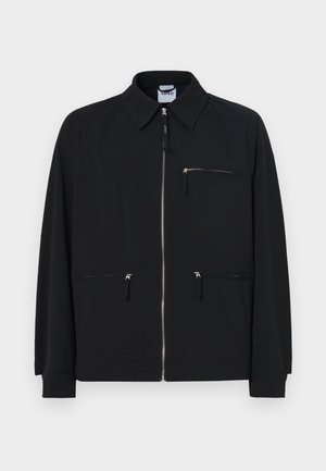 Veste noire en tissu léger, dotée d'une fermeture éclair à l'avant, de deux poches latérales et d'une poche poitrine zippée en haut.