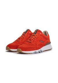 Sneaker in suede rosso con superficie testurizzata, intersuola bianca e suola in gomma color cuoio. Presentano lacci e un piccolo logo di lato.