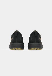 Black athletic shoes with textured fabric upper, matching heel tab, and gum rubber outsole. Features subtle orange accents.