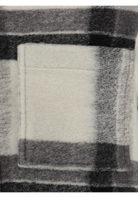 Fleece-Stoff im gesteppten Muster mit großen schwarz-grauen Karos auf hellem Hintergrund. Mit einer quadratischen aufgesetzten Tasche. Weiche Textur.