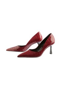Pair of glossy dark red crocodile pattern pointed-toe high heels with slender metallic stiletto heels on white background.