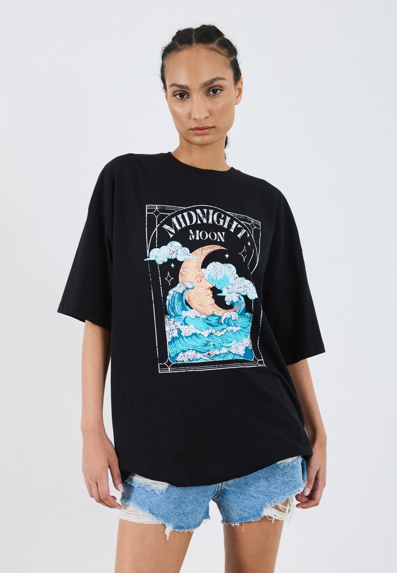 Svart oversized t-shirt med en färgglad grafik av vågor och en måne, med orden "MIDNIGHT MOON" i en dekorativ ram.