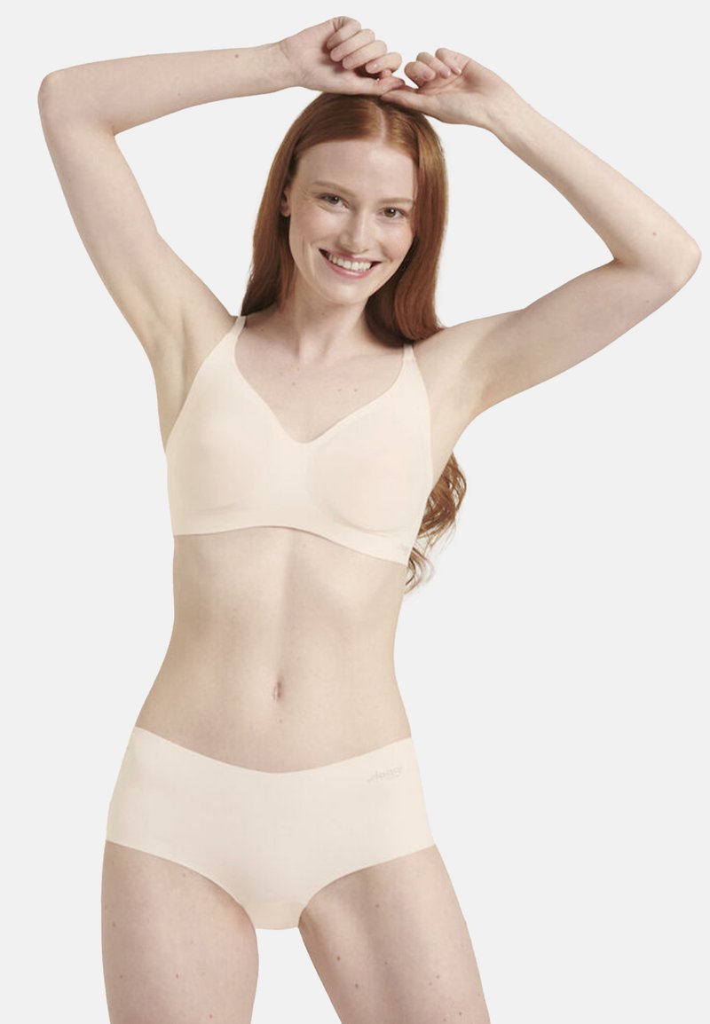Beige saumatön pitot ja alushousut, jotka on valmistettu pehmeästä kankaasta. Pitovassa on säädettävät olkaimet ja sileä pinta. Alushousut ovat minimalistisessa designissa.