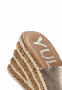 Sandal de plataforma de corcho marrón con una suela intermedia texturizada y una tira metálica brillante. La plantilla presenta un detalle de logo en relieve.