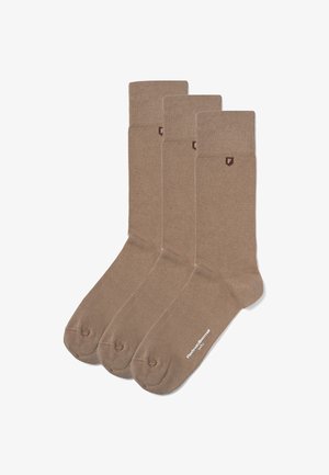 Drie paar bruine sokken met een gladde textuur, geribbelde bovenkanten en een klein logo op de boord. Elke sok heeft verstevigde tenen.