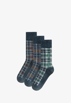 Drei Paar Wollsocken mit gerippten Bündchen, jeweils mit unterschiedlichen Karomustern in Blau-, Braun- und Grüntönen auf weißen Hintergründen.