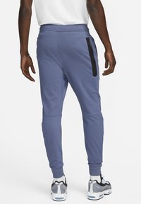 Blauwe joggingsbroek met een tapered fit, gemaakt van zachte stof. Kenmerkt zich door een zwarte ritszak, elastische tailleband en ribgebreide manchetten.
