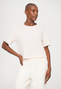 Tricou scurt, de culoare roz deschis, cu mâneci scurte, confecționat dintr-un material moale, având un detaliu mic cu logo pe partea din față.
