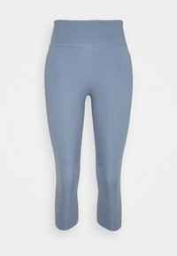 Vaaleansiniset, kolmannelta neljännekset pituudelta olevat leggingsit, joissa on leveä vyötärönauha ja joustava kangas. Saumayksityiskohdat ovat näkyvissä jaloissa.