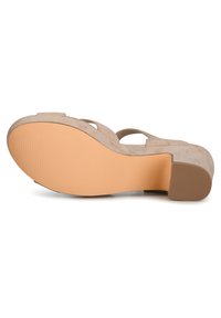Beige suède sandaal met hoge hak, een taps toelopende hak, een gladde tan rubberen zool en een crisscross bandontwerp.