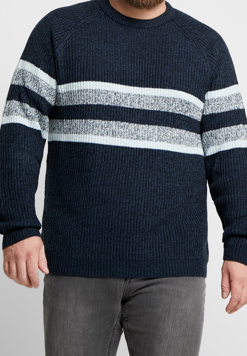 Maglione a coste blu con strisce orizzontali in azzurro chiaro e bianco sul petto. Maniche lunghe e scollatura rotonda.