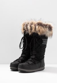 Zwarte winterlaarzen met een waterdichte buitenkant, een bontafwerking aan de bovenkant, verstelbare veters en een getextureerde rubberen zool voor verbeterde grip.