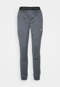 Šedé tepláky s černým elastickým pasem, na kterém je nápis "THE NORTH FACE" a malé bílé logo na horní části stehna.