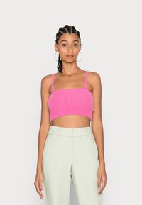 Top cropped rosa fuzzy com decote quadrado e alças finas. Combinado com calças altas de cintura alta verde claro e ajustadas.