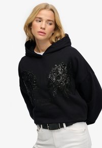 Czarna bluza oversize z haftem z kwiatowych cekinów na piersi, z teksturowanym wykończeniem i przednią kieszenią typu kangur.