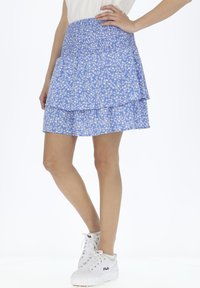 Gonna floreale blu con un design a strati, vita elasticizzata e lunghezza corta, abbinata a sneakers bianche.