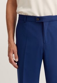 Marineblaue maßgeschneiderte Hose aus einem glatten Material, mit einem Knopfverschluss, vorderen Falten und einem geraden Bein Design.