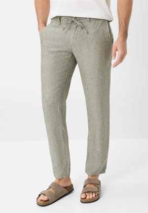 Linen blend trousers in light green with a textured finish, featuring a drawstring waist and two side pockets, paired with brown sandals.