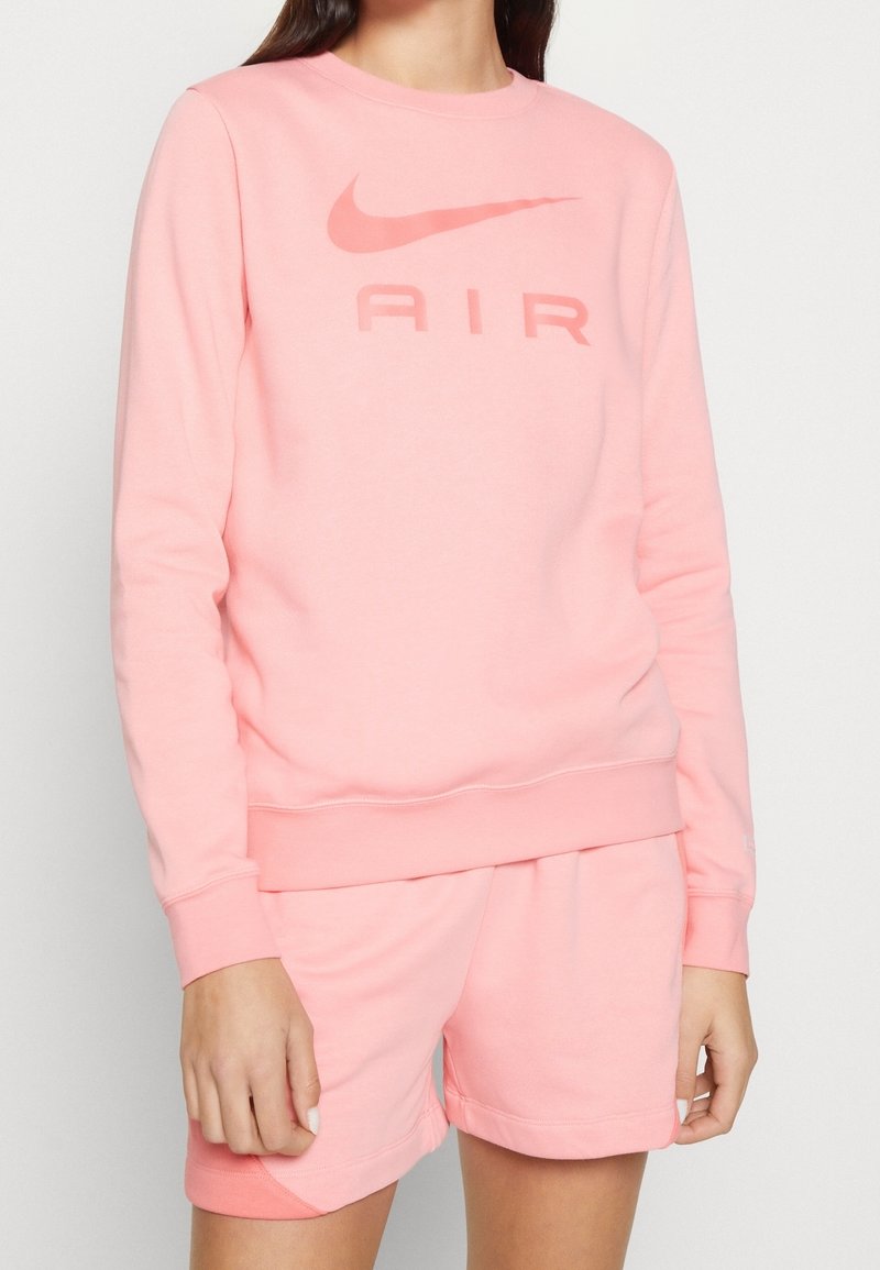 Sweat-shirt rose clair en tissu doux, doté d'un col rond, de manches longues, et d'un graphisme audacieux "AIR" au centre.