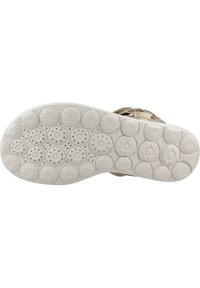 Suola delle calzature caratterizzata da un design in gomma bianca testurizzata con motivi circolari e fori di ventilazione. Accentuata da una morbida tracolla beige.