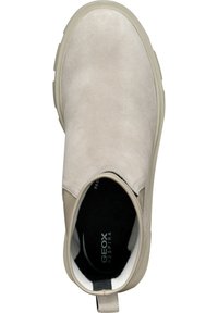 Chaussure beige à enfiler avec tige en daim, bout rond, panneaux latéraux élastiques et semelle en caoutchouc ; présente le logo Geox sur la semelle intérieure.