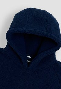 Granatowa polarowa bluza z kapturem o miękkiej teksturze, oversizowym kapturze i przedniej kieszeni. Materiał jest puszysty i przytulny, idealny na ciepło.