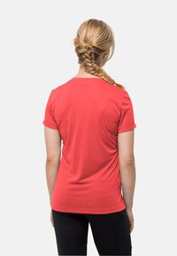 Rode korte mouwen t-shirt met een ronde hals, zachte textuur en een getailleerd ontwerp, gecombineerd met zwarte broek. Gezien vanuit de achterkant.
