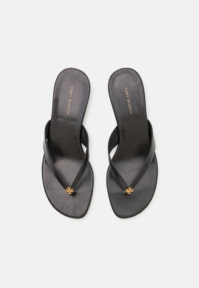 Pair of black leather Tory Burch thong sandals with gold logo embellishments on the straps, shown from above on a white background.