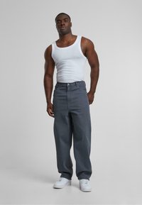 Grijze rechte jeans met een hoge taille, gecombineerd met een witte tanktop en witte sneakers. De stof lijkt glad met minimale details.