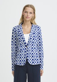 Blazer en tissu blanc avec motifs d'étoiles bleues. Doté d'un col cranté, d'une fermeture à un bouton et de poches avant. Texture lisse.