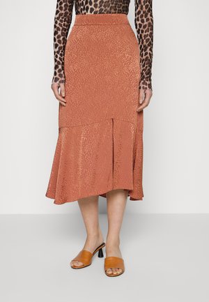 Saia midi evasê em tons de ferrugem com uma textura subtil e padrão de leopardo, apresentando uma cintura alta e uma bainha em camadas. Combinada com sapatos de salto aberto em tom castanho.