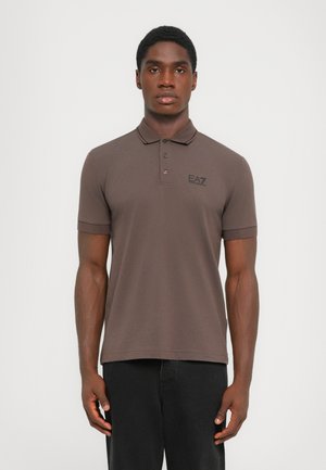 Brown polo shirt with a classic collar, featuring short sleeves and a subtle logo in black. Smooth texture and fitted design.