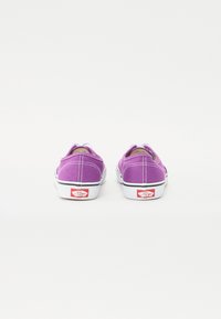Purple canvas shoes with white soles, contrasting black trim, and red branding on the heel. Features a slip-on design.