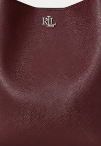 Superficie in pelle testurizzata color burgundy con dettaglio logo "RLL" in argento centrato vicino al bordo superiore.