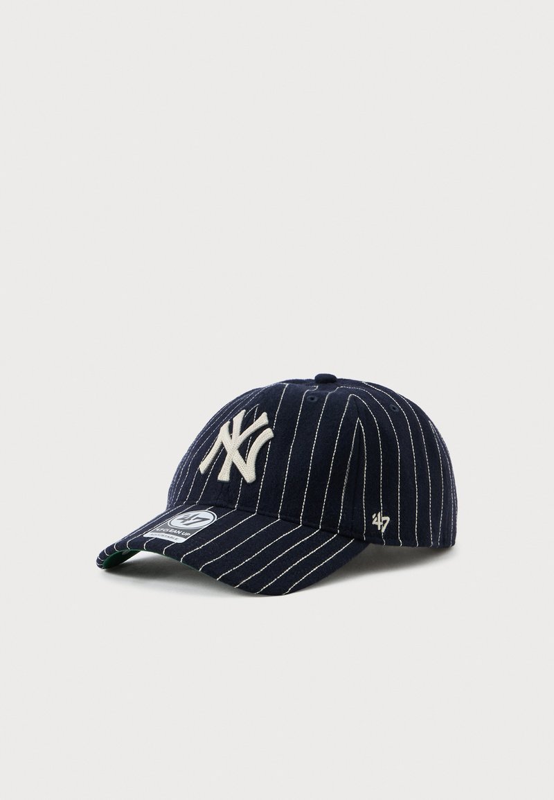Marineblauwe baseballpet met witte streepjes, geborduurd logo op de voorkant, gebogen klep, en een klein logo aan de zijkant.