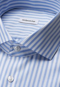 Lichtblauw en wit gestreept overhemd met visgraatpatroon, voorzien van een klassieke kraag en een label met "seidensticker."