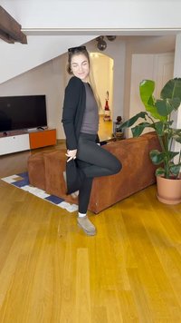 Must must üle halli pluusi ja mustade retuuside, millele on lisatud pruunid pahkluu saapad. Taustal on pruun diivan ja pottitaim.