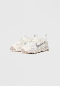 Balta ir šviesiai pilka Nike bėgimo batelių pora su tinkline ir sintetine danga, tekstūruotais pados ir tempiamaisiais užtraukimais ant vienodos fono.