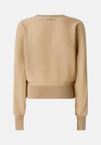 Pull beige avec une finition texturée, des poignets côtelés et un ourlet droit. Présente une petite étiquette logo au niveau de l'encolure arrière.