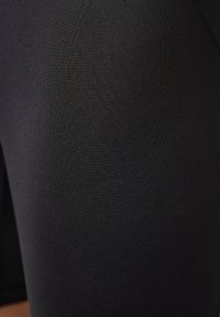 Pantaloni sportivi neri realizzati in tessuto liscio e elasticizzato. Caratterizzati da un design elegante e senza cuciture con finitura opaca, adatti per l'abbigliamento sportivo.