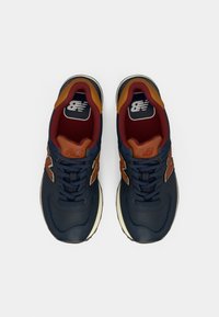 Navy blue sneakers with brown accents, textured leather and mesh upper, lace-up design, white midsole, and logo on tongue.