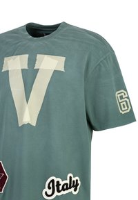 Groene katoenen T-shirt met een grote witte "V" graphic, een rode hexagon patch, geborduurd "Italië," en witte nummer "6" op de mouw.